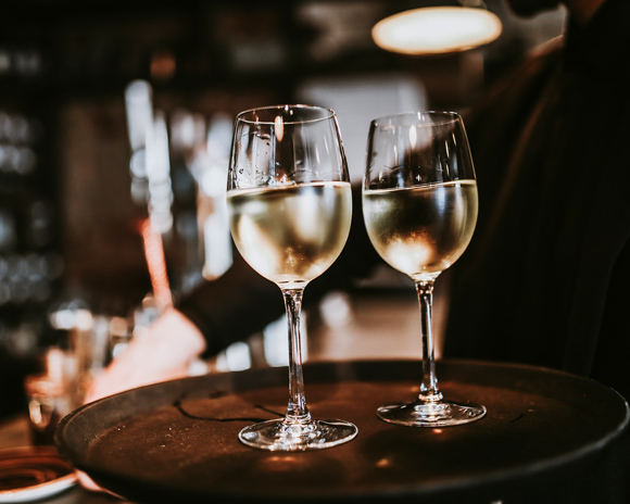 white wine glasses being carried on tray by waiter